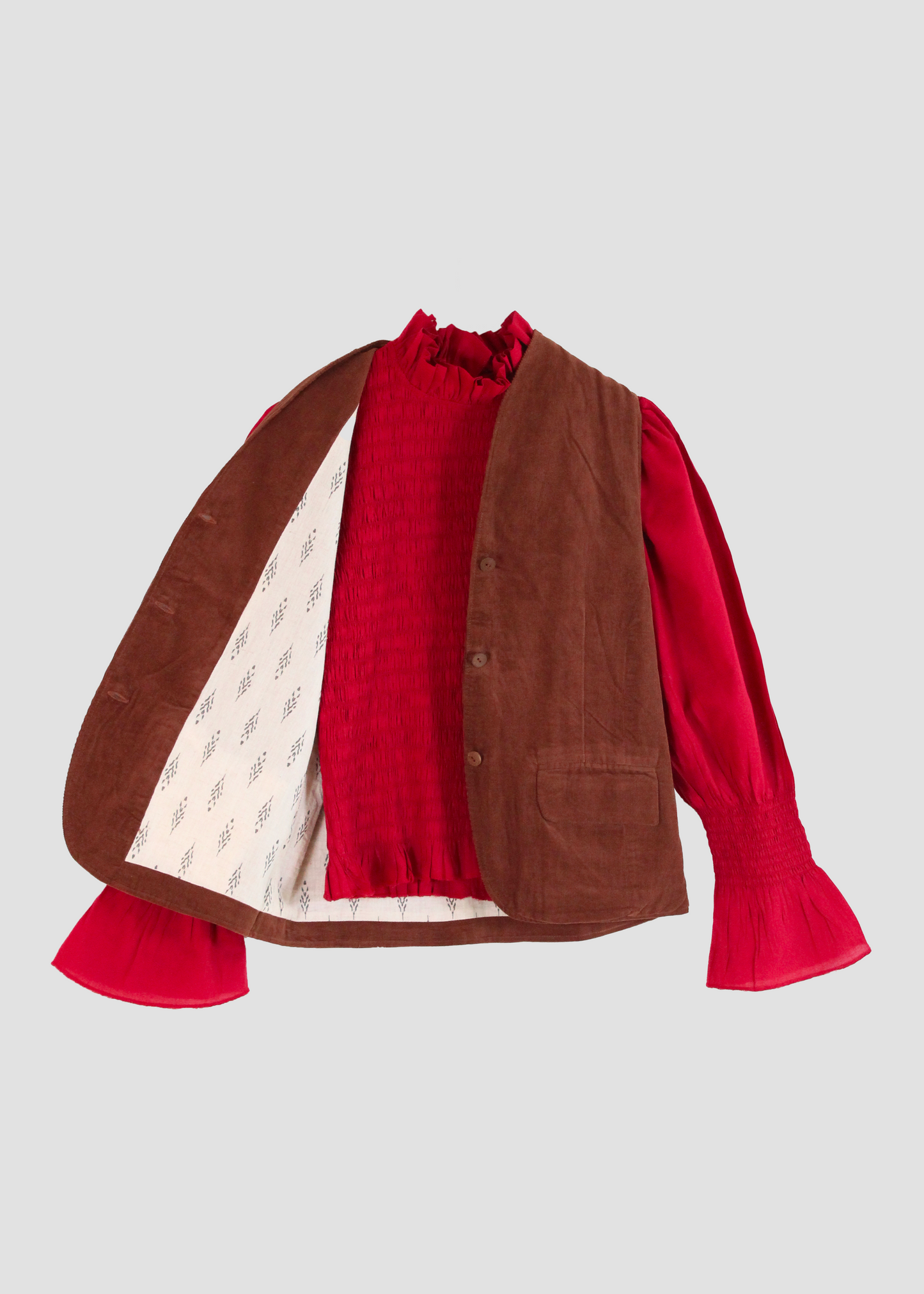 Gilet Madeleine in velluto a coste marrone di IGI Ama, smanicato marrone con fodera in cotone a motivo bianco e grigio. Realizzato in velluto a coste con fodera in cotone stampato. Stile elegante e raffinato, prodotto eticamente in India. Lavabile in lavatrice a 30°C, stirare a bassa temperatura.