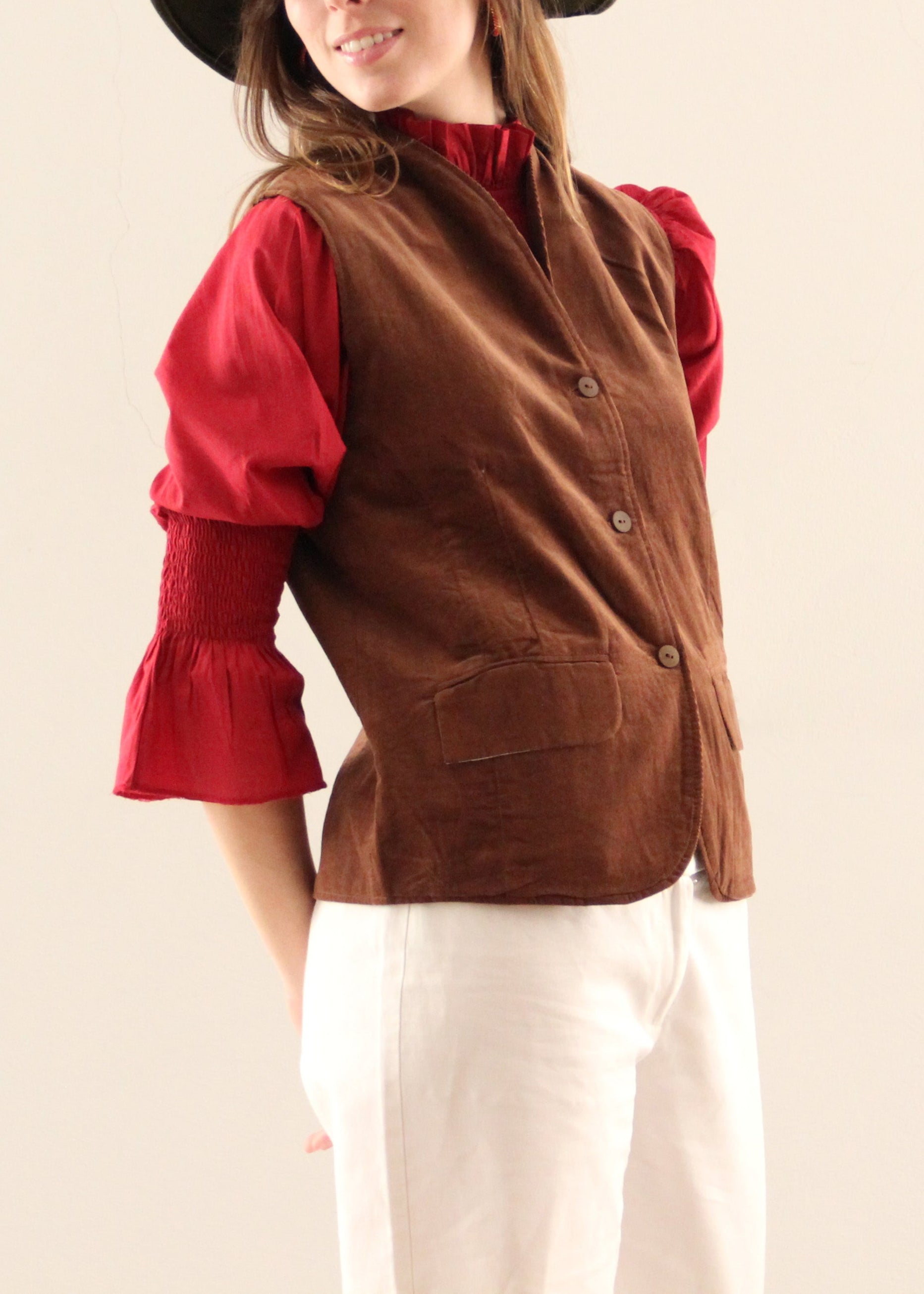 Gilet Madeleine in velluto a coste marrone di IGI Ama, smanicato marrone con fodera in cotone a motivo bianco e grigio. Realizzato in velluto a coste con fodera in cotone stampato. Stile elegante e raffinato, prodotto eticamente in India. Lavabile in lavatrice a 30°C, stirare a bassa temperatura.