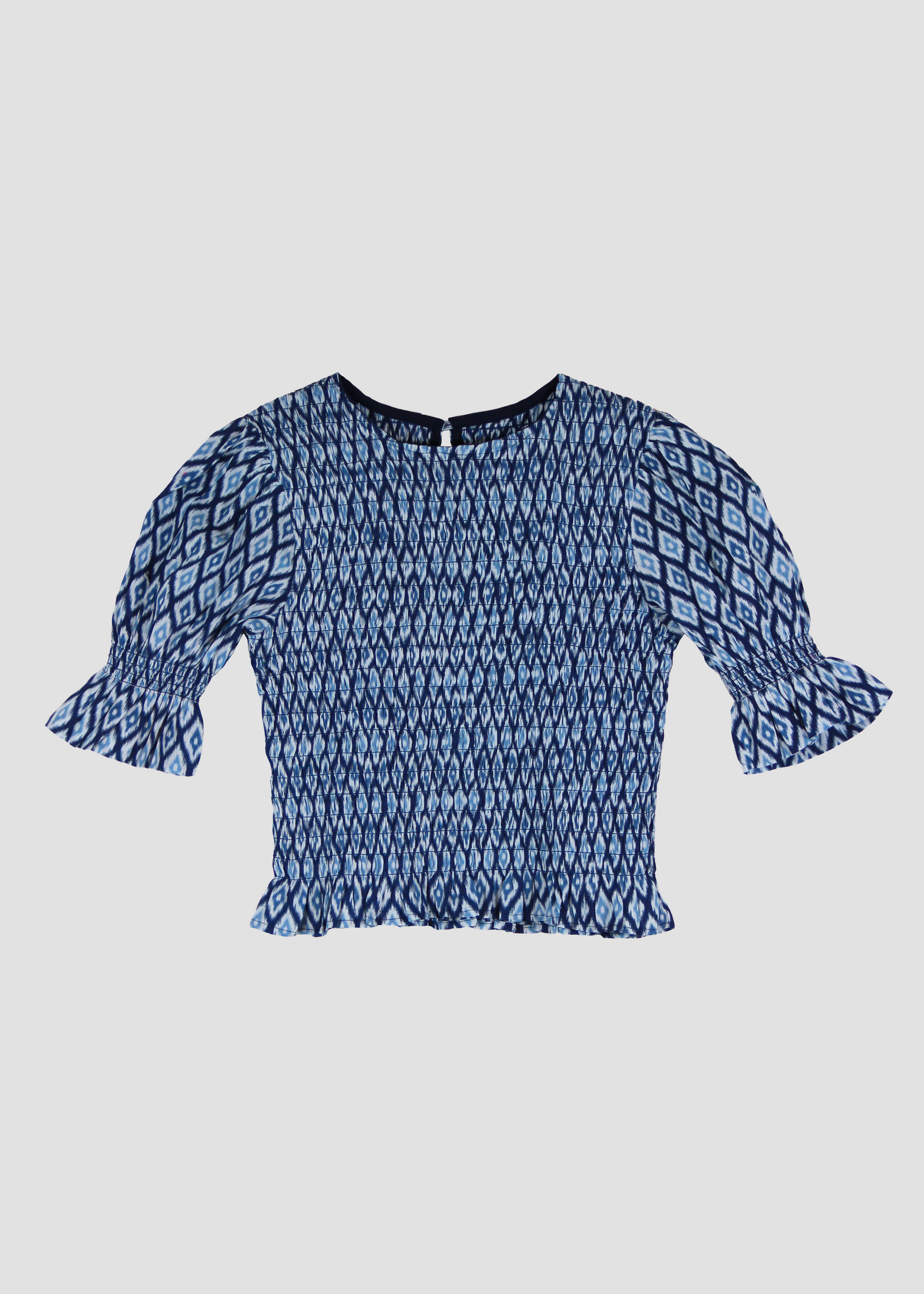 Holi Blouse – Camicetta ikat a maniche corte, realizzata in 100% cotone con maniche a sbuffo e arricciature elastiche su busto e maniche. Vestibilità elasticizzata e confortevole, adatta a tutte le corporature. Taglia unica. Prodotta eticamente in India. Cura delicata: lavare a 30°C, stirare a bassa temperatura.
