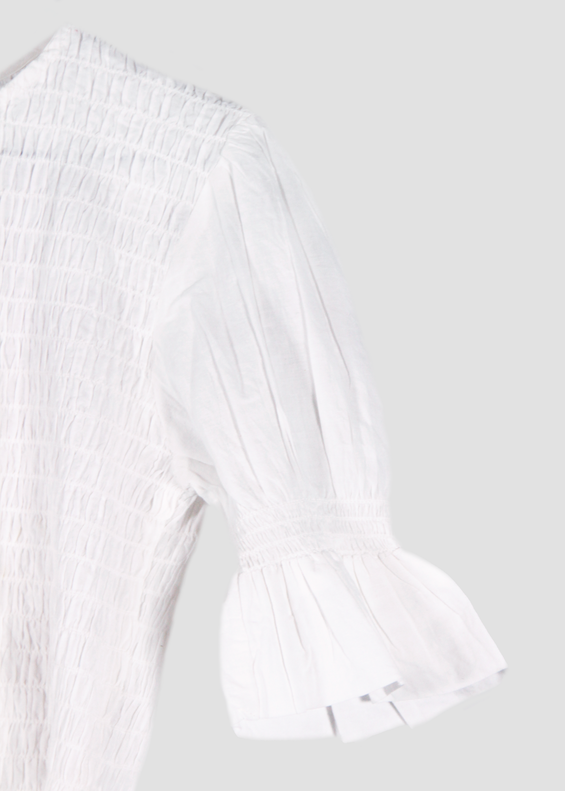Holi Blouse – Camicetta bianca a maniche corte, realizzata in 100% cotone con maniche a sbuffo e arricciature elastiche su busto e maniche. Vestibilità elasticizzata e confortevole, adatta a tutte le corporature. Taglia unica. Prodotta eticamente in India. Cura delicata: lavare a 30°C, stirare a bassa temperatura.