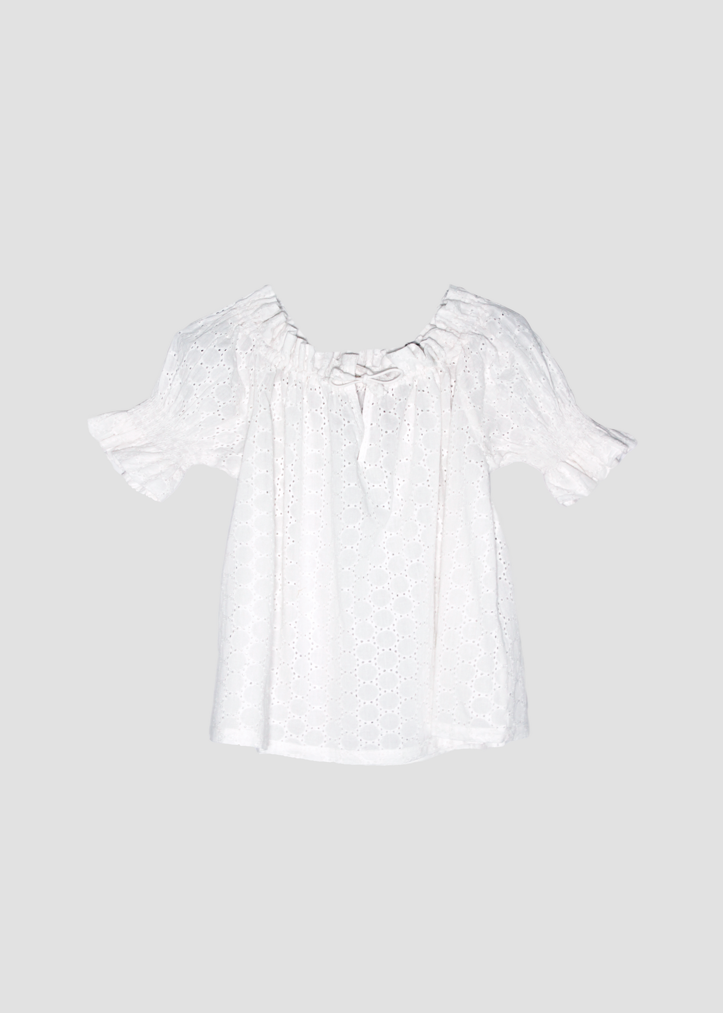 Blusa arricciata da donna in cotone bianco con trama sangallo, modello Pimpa shirt di IGI AMA, 100% cotone, con laccetto sullo scollo e maniche elasticizzate a sbuffo, tessuto elastico che si adatta a tutte le corporature, prodotta in India, ideale per look estivi e casual.