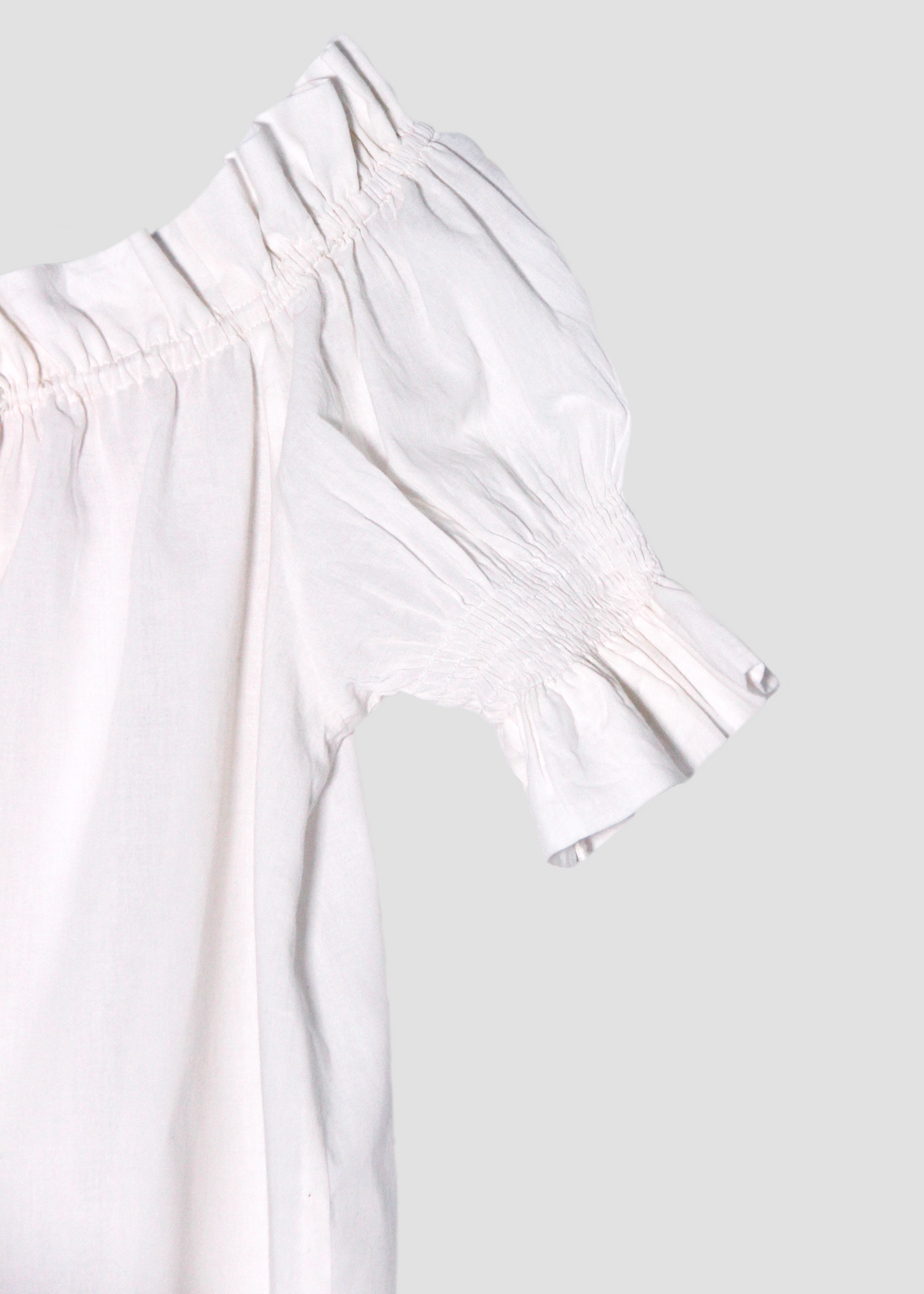 Blusa arricciata da donna in cotone bianco, modello Pimpa shirt di IGI AMA, 100% cotone, con laccetto sullo scollo e maniche elasticizzate a sbuffo, tessuto elastico che si adatta a tutte le corporature, prodotta in India, ideale per look estivi e casual.