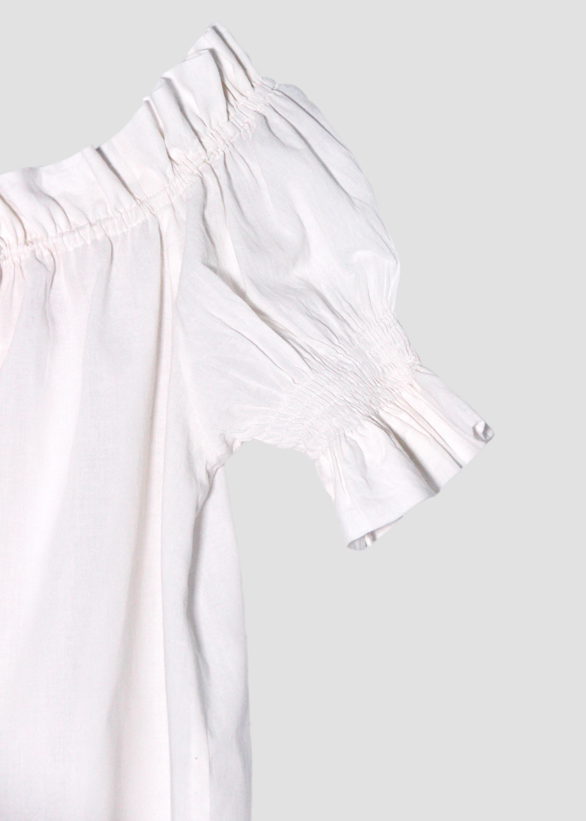 Blusa arricciata da donna in cotone bianco, modello Pimpa shirt di IGI AMA, 100% cotone, con laccetto sullo scollo e maniche elasticizzate a sbuffo, tessuto elastico che si adatta a tutte le corporature, prodotta in India, ideale per look estivi e casual.