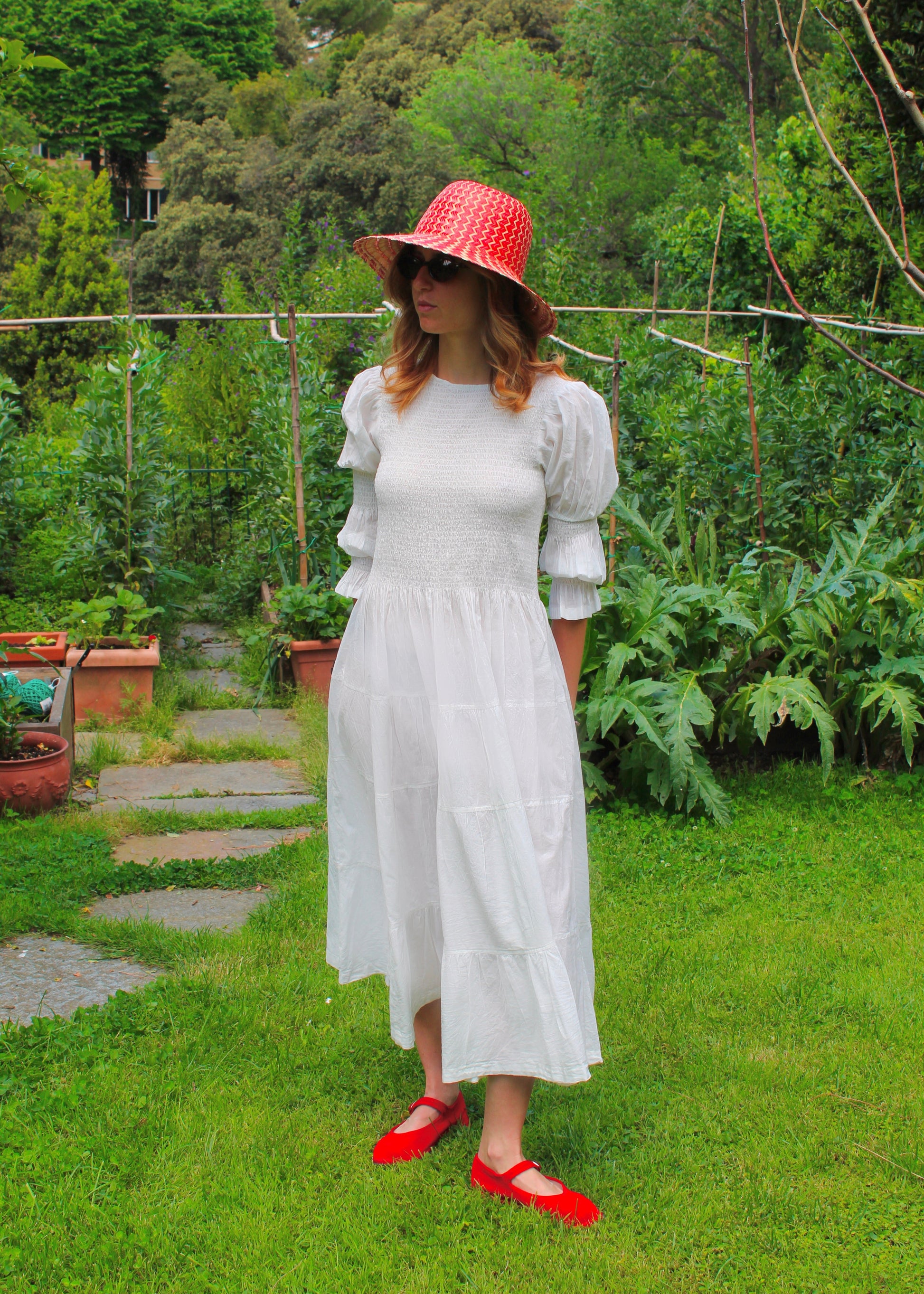 Primula Dress di IGI AMA, vestito midi in tessuto bianco 100% cotone, maniche lunghe a sbuffo con doppia cucitura elastica, busto arricciato, taglia unica e tessuto elasticizzato che si adatta a tutte le corporature, lunghezza fino alla caviglia, prodotto in India, ideale per un look comodo, femminile e artigianale.