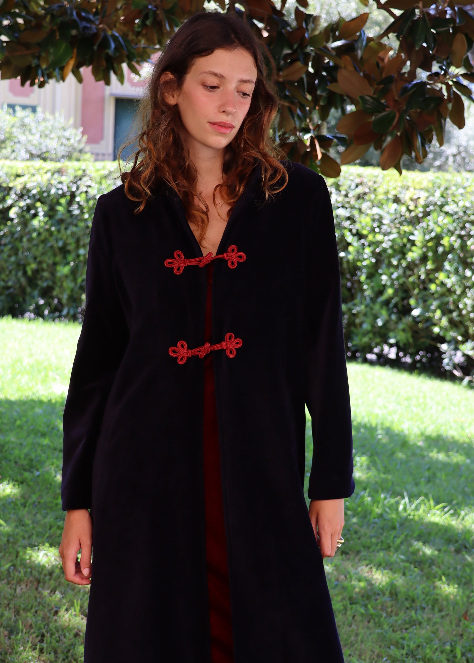 Alamari Coat in velluto blu di IGI Ama, cappotto blu con alamari rosso, collo alla coreana e bottoni a nodo. Spalle strutturate e fodera in poliestere. Prodotto in India, con un design elegante e raffinato. Lavare a secco, stirare a bassa temperatura, non candeggiare.