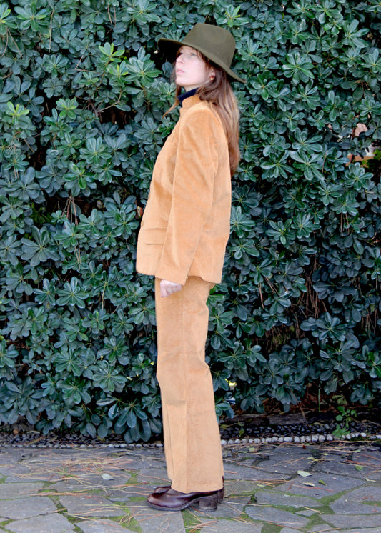 Abito in velluto a coste 1970 Suit di IGI AMA color senape, abito in velluto a coste color senape con giacca e pantaloni. Giacca con vita aderente, spalle strutturate e collo alla coreana. Fodera in poliestere, la modella è alta 170 cm e indossa una taglia S. Pantaloni in velluto a coste con pinces anteriori, vestibilità regolare, disponibili nelle taglie M e L. Prodotto in India con un design elegante e versatile. Solo lavaggio a secco, stiratura a bassa temperatura, non candeggiare.