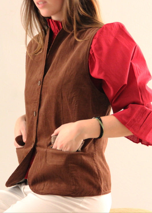 Gilet Madeleine in velluto a coste marrone di IGI Ama, smanicato marrone con fodera in cotone a motivo bianco e grigio. Realizzato in velluto a coste con fodera in cotone stampato. Stile elegante e raffinato, prodotto eticamente in India. Lavabile in lavatrice a 30°C, stirare a bassa temperatura.