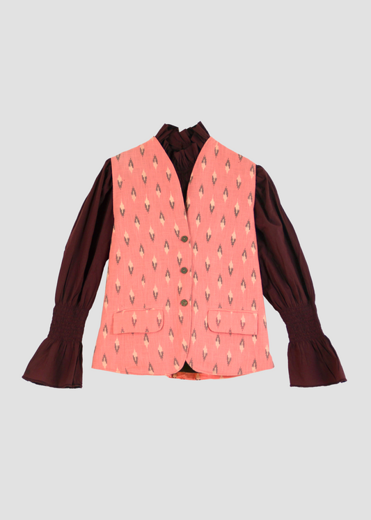Gilet Madeleine in lino rosa di IGI Ama, smanicato rosa salmone con motivo a rombi, metà rosa chiaro e metà marrone. Realizzato in lino con pattern ikat e interno in velluto a coste. Stile elegante e raffinato, prodotto eticamente in India. Lavabile in lavatrice a 30°C, stirare a bassa temperatura.