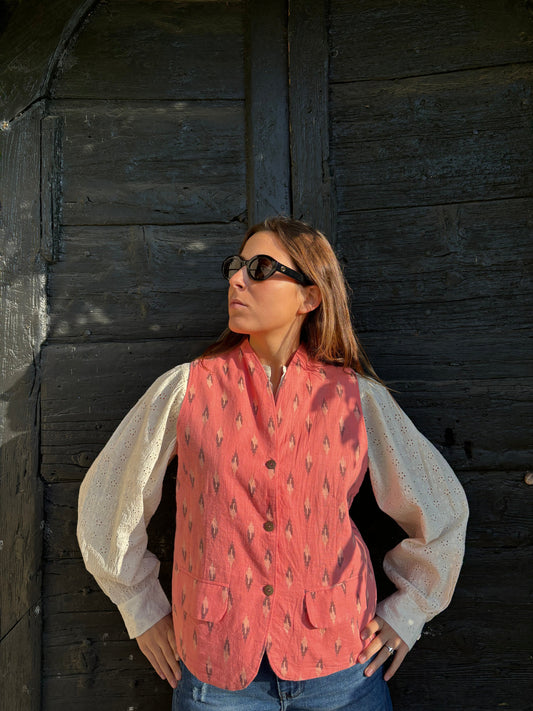Gilet Madeleine in lino rosa di IGI Ama, smanicato rosa salmone con motivo a rombi, metà rosa chiaro e metà marrone. Realizzato in lino con pattern ikat e interno in velluto a coste. Stile elegante e raffinato, prodotto eticamente in India. Lavabile in lavatrice a 30°C, stirare a bassa temperatura.