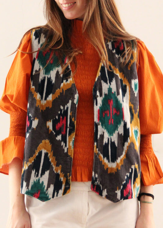 Gilet Polo in velluto nero di IGI Ama, smanicato in velluto con motivo colorato all'esterno. Realizzato in India con fodera in cotone 100% a fantasia. Taglia unica (torace 50 cm per lato, lunghezza 60 cm, giromanica 26 cm). Stile elegante con un tocco boho chic. Lavare a secco, stirare a bassa temperatura, non candeggiare.