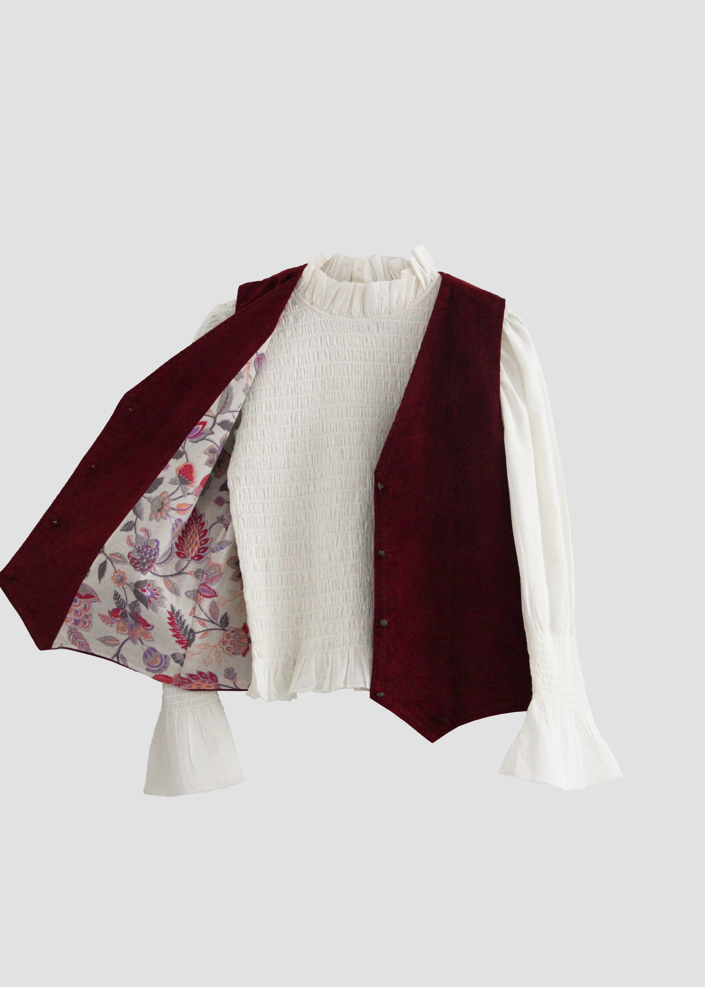 Gilet Polo in Bordeaux Velvet di IGI AMA, gilet in velluto bordeaux con fodera a fantasia floreale rosa e grigia. Realizzato in India con fodera a fantasia in 100% cotone. Taglia unica (torace 50 cm per lato, lunghezza 60 cm, ascella 26 cm). Stile elegante con un tocco boho chic. Solo lavaggio a secco, stirare a bassa temperatura, non candeggiare.