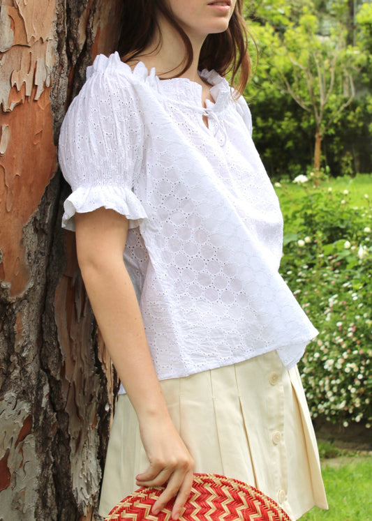 Blusa arricciata da donna in cotone bianco con trama sangallo, modello Pimpa shirt di IGI AMA, 100% cotone, con laccetto sullo scollo e maniche elasticizzate a sbuffo, tessuto elastico che si adatta a tutte le corporature, prodotta in India, ideale per look estivi e casual.