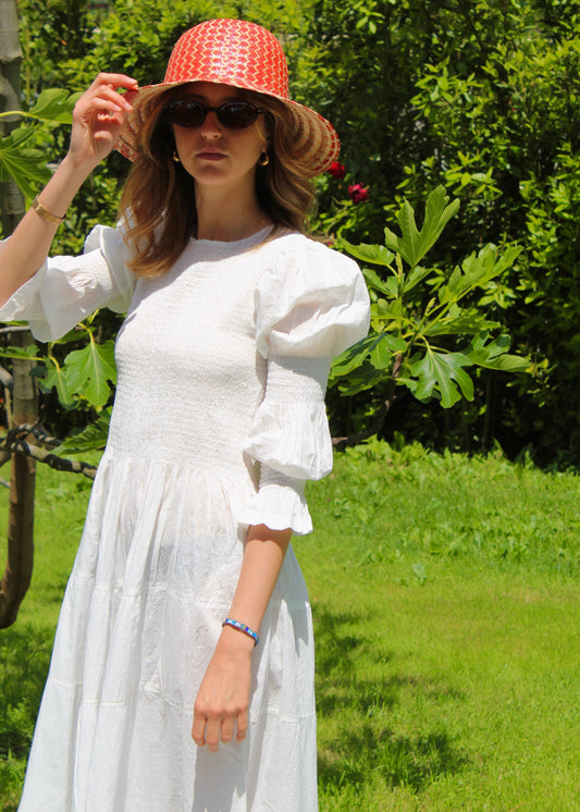 Primula Dress di IGI AMA, vestito midi in tessuto bianco 100% cotone, maniche lunghe a sbuffo con doppia cucitura elastica, busto arricciato, taglia unica e tessuto elasticizzato che si adatta a tutte le corporature, lunghezza fino alla caviglia, prodotto in India, ideale per un look comodo, femminile e artigianale.