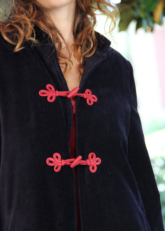 Alamari Coat in velluto blu di IGI Ama, cappotto blu con alamari rosso, collo alla coreana e bottoni a nodo. Spalle strutturate e fodera in poliestere. Prodotto in India, con un design elegante e raffinato. Lavare a secco, stirare a bassa temperatura, non candeggiare.